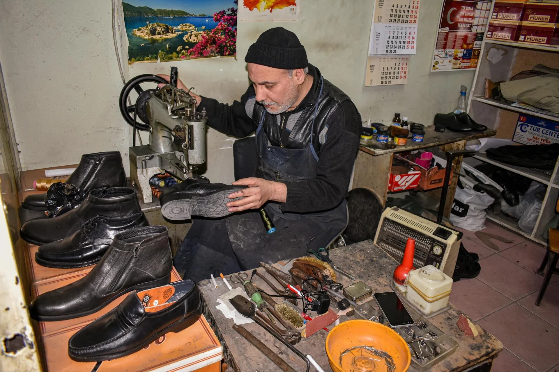 Maître cordonnier réparant des chaussures avec une machine à coudre à son établi dans un atelier traditionnel